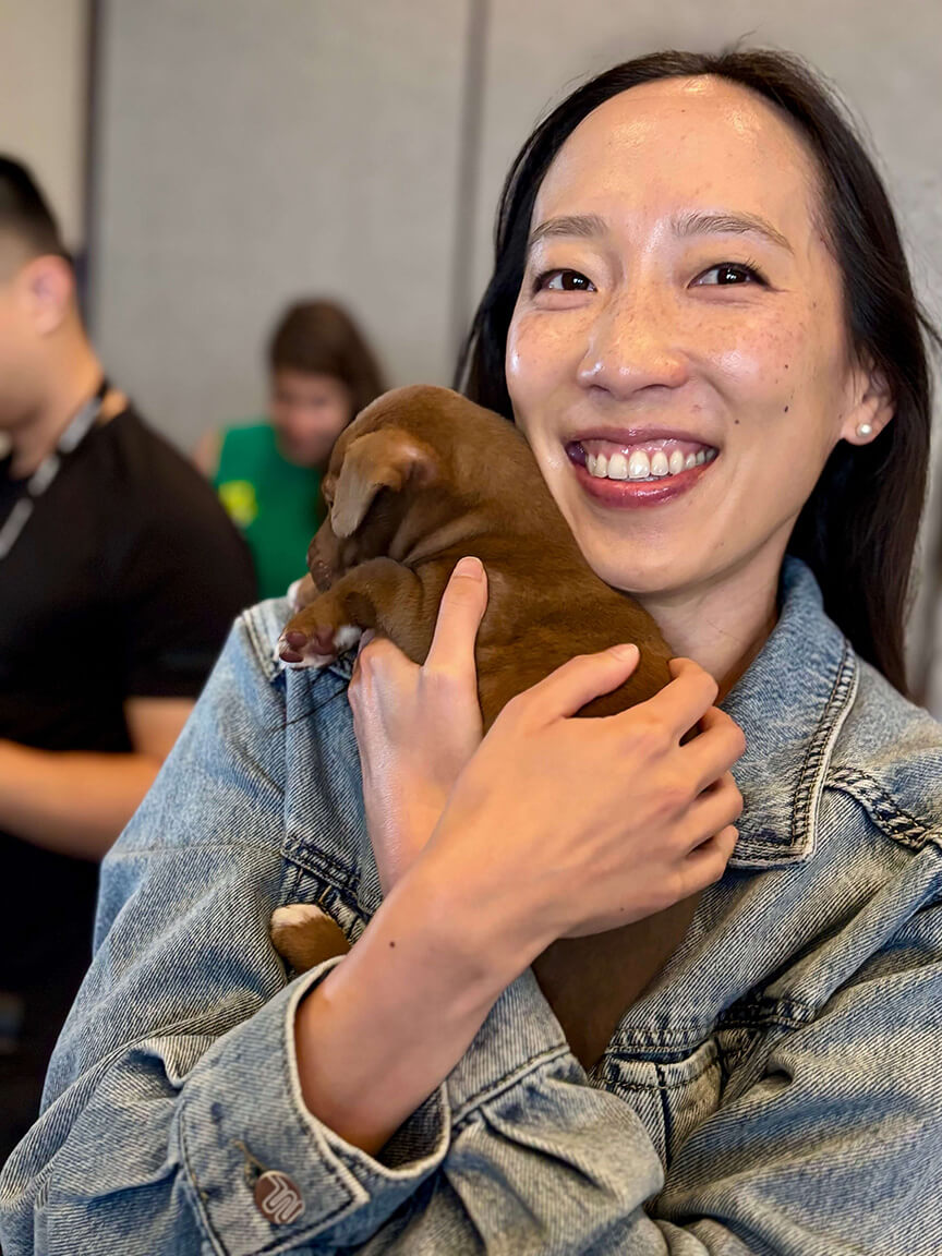 Momentum 2025 attendee holds a puppy during puppy yoga